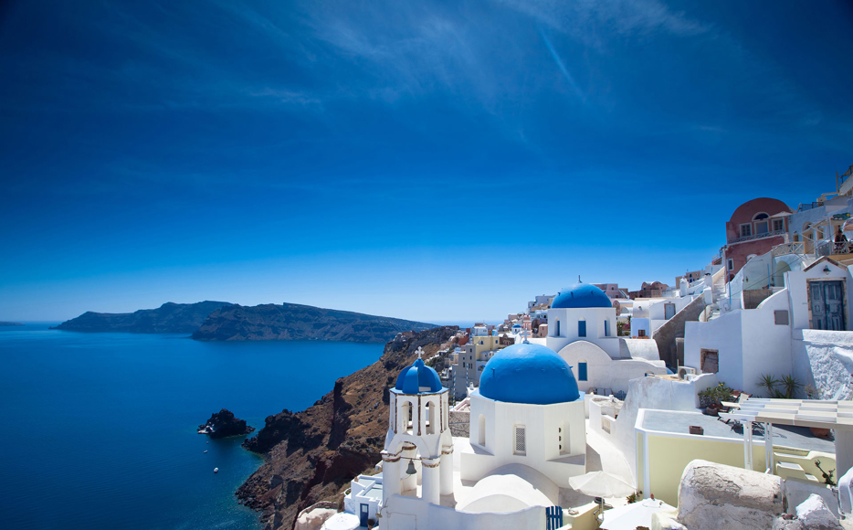 Iconic view of whitewashed houses and blue-domed churches overlooking the caldera in Santorini, Greece