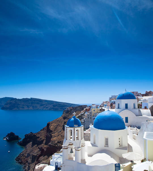 Iconic view of whitewashed houses and blue-domed churches overlooking the caldera in Santorini, Greece