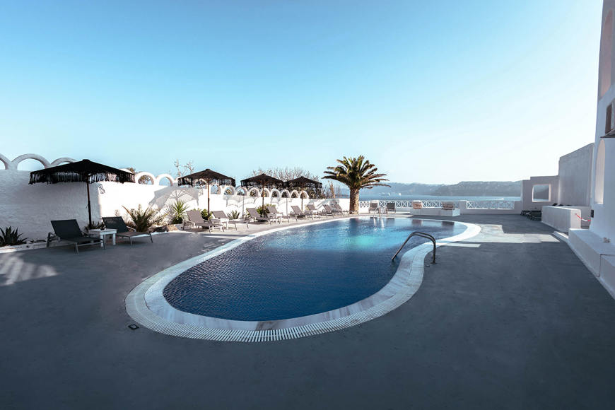 Serene poolside area at Santorini View Hotel by Trend Hotels with sea view and palm trees