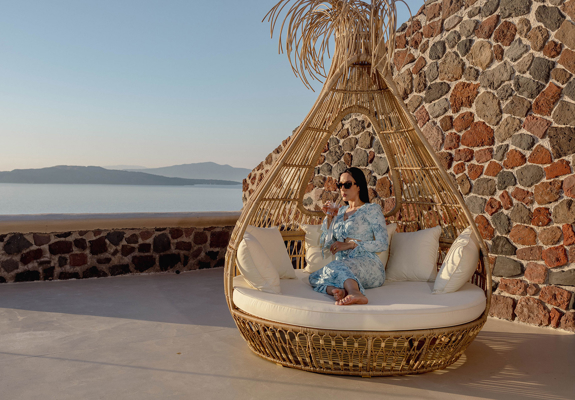 Guest relaxing on outdoor lounge chair with caldera view at Grand Ambassador by Trend Hotels in Santorini