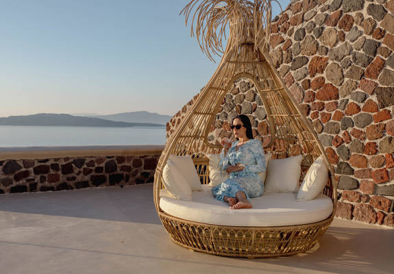 Guest relaxing on outdoor lounge chair with caldera view at Grand Ambassador by Trend Hotels in Santorini