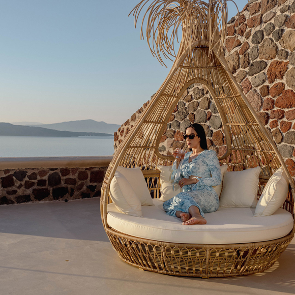 Guest relaxing on outdoor lounge chair with caldera view at Grand Ambassador by Trend Hotels in Santorini